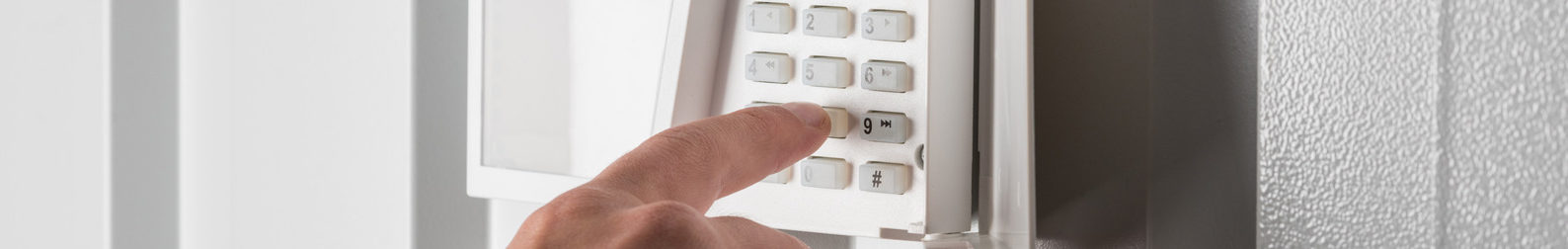 person typing on keypad of security alarm, security system concept